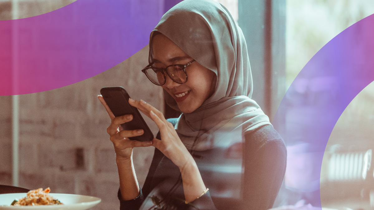 A hijabi woman happily using digital devices