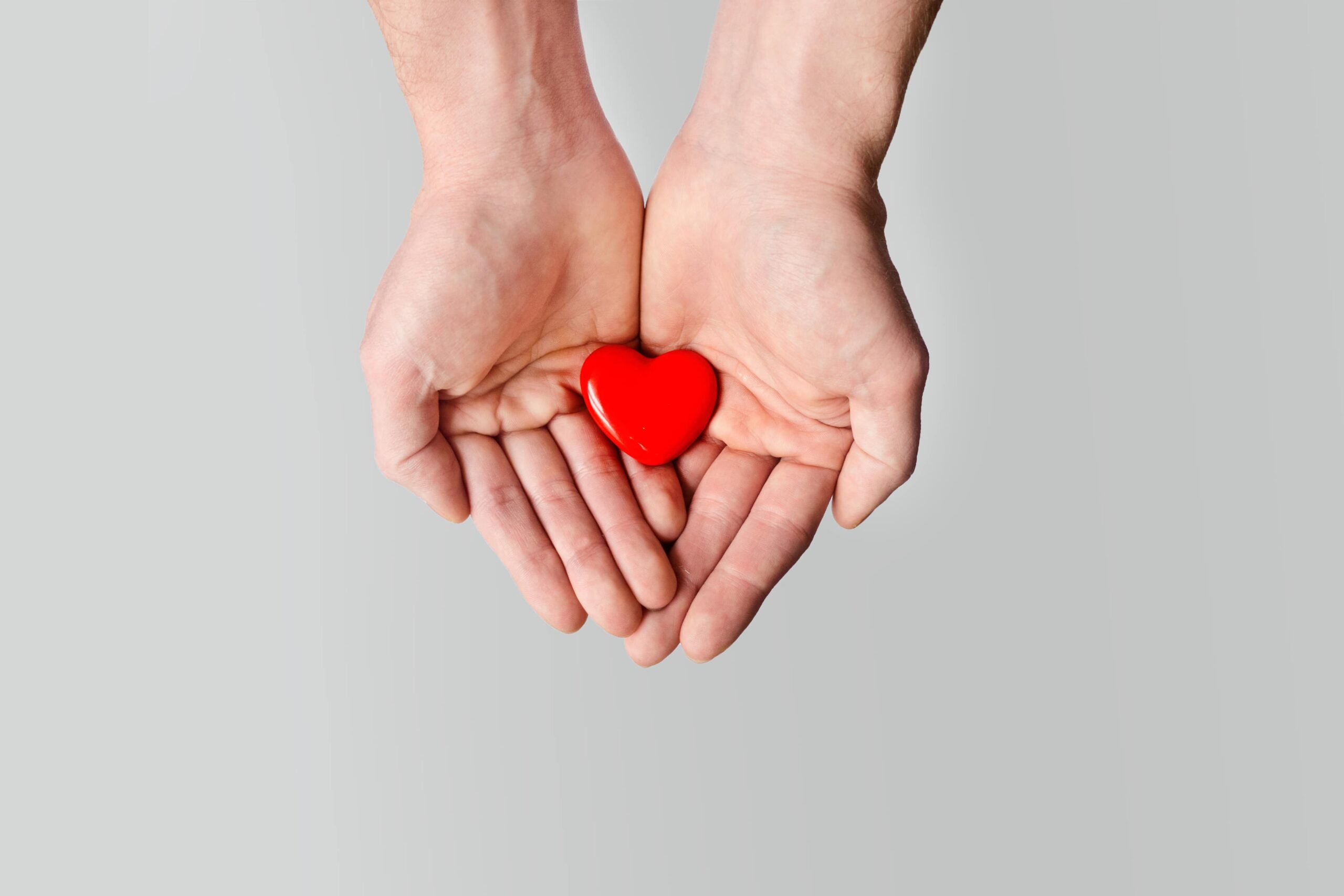 holding a red heart in the palms to honor yourself and others