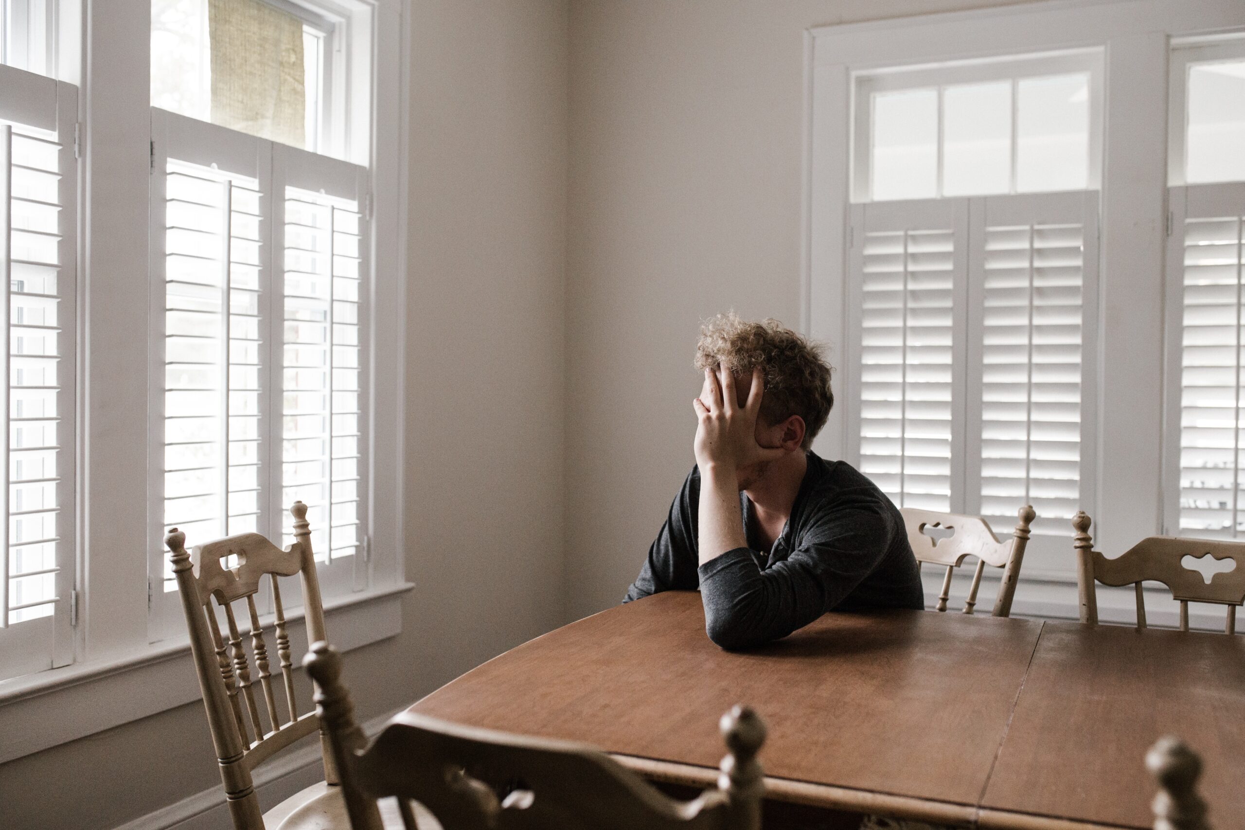 demotivated, islolated, man at table alone in his house