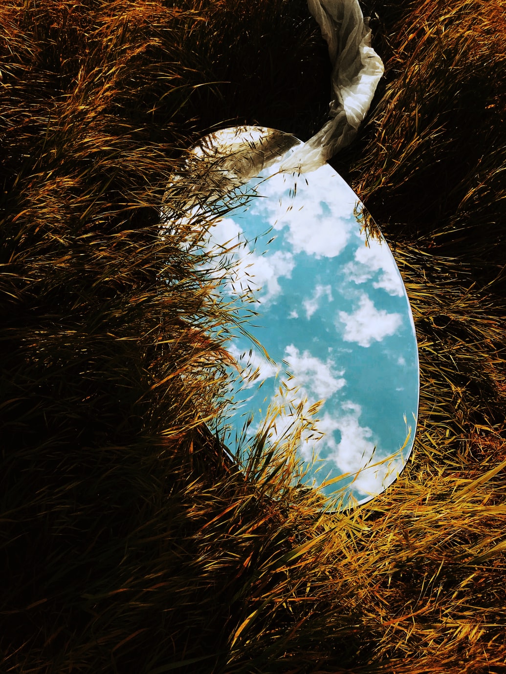 mirror reflecting the clouds on grass