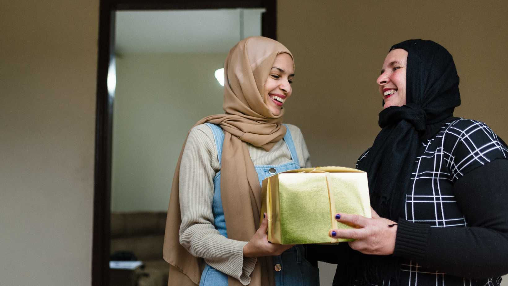 two muslim women giving each other gifts