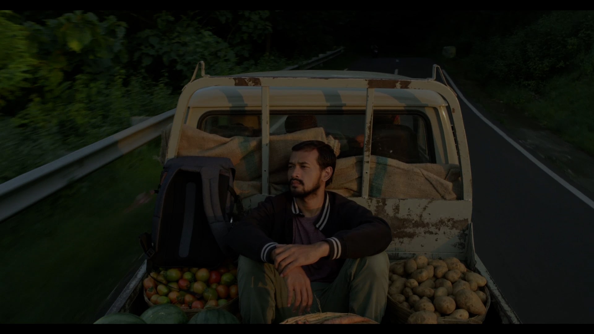 A man sitting on the back of a small lorry.
