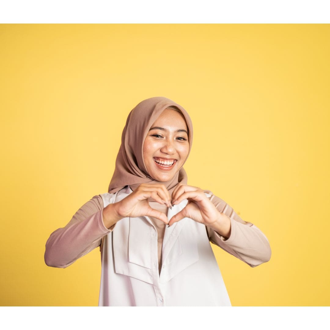 Muslim Hijabi girl making a heart with her hands and smiling